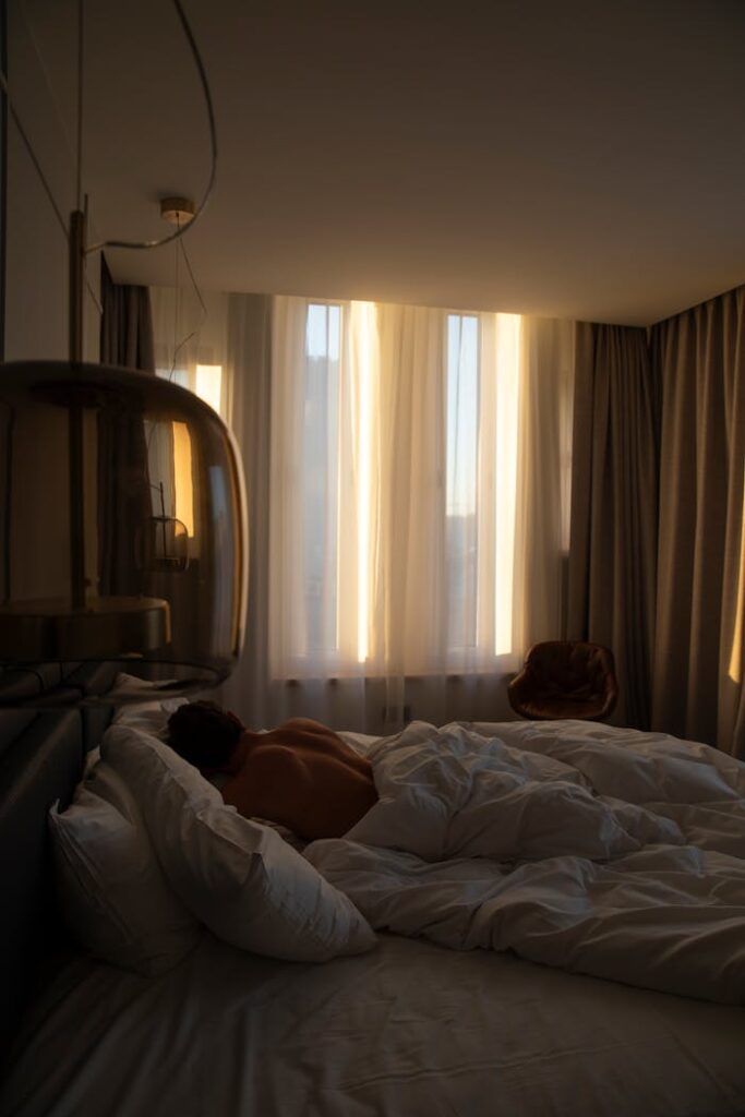 A Shirtless Man Lying in Bed in the Bedroom in the Morning