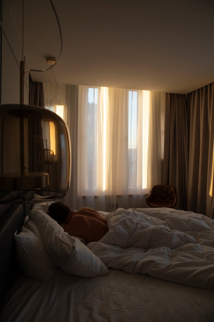A Shirtless Man Lying in Bed in the Bedroom in the Morning 